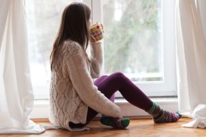 young-woman-having-hot-tea-near-window