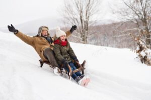 grandfather-and-granddaughter-sledding-down-hill