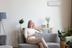 middle-aged-woman-looking-relaxed-on-sofa-with-mini-split-on-wall